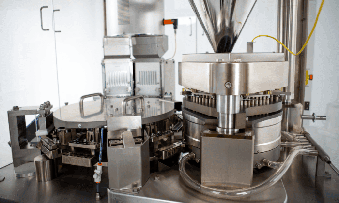 Close-up of a stainless steel automatic capsule filling machine for nutraceutical and pharmaceutical production.