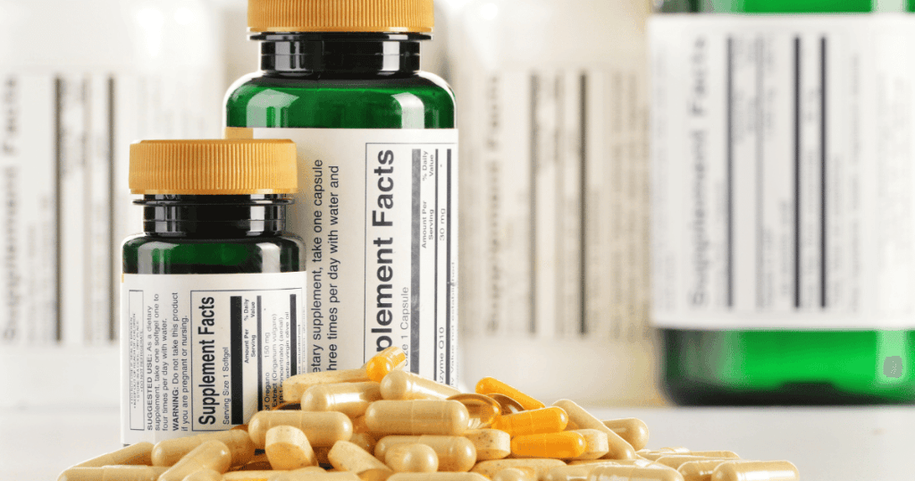 A pile of capsule supplements in front of supplement product bottles, with their supplement facts data label facing forward.